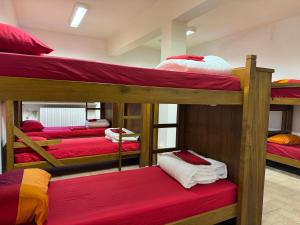 een kamer met 4 stapelbedden met rode lakens bij Rifugio Nido del Biancone in Bosio