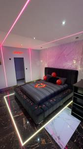 Cama negra en habitación con luces rosas en HIGHFIELD PRIVATE SPA APARTMENT, en Bradford