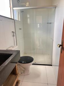uma casa de banho com um WC e uma cabina de duche em vidro. em Flat Xainã em Taipu