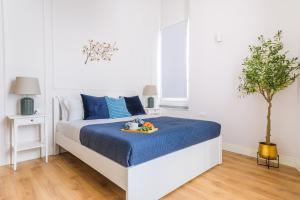 a white bedroom with a bed with a blue bedspread at L'Opera Rooms & Suite in La Spezia
