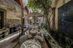 un restaurante con mesas, sillas y sombrilla en Casa No Name Small Luxury Hotel, en San Miguel de Allende