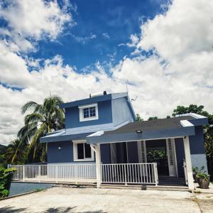 ein blaues Haus mit einer weißen Veranda in der Unterkunft Villa F4 chic avec jacuzzi en Martinique in Le Lamentin