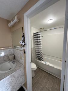 a bathroom with a tub and a toilet and a sink at Motel Nicholas in Omak