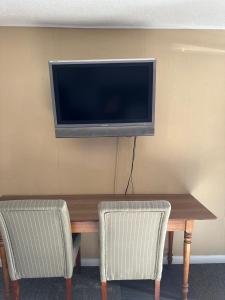 a television on a wall above a table with two chairs at Motel Nicholas in Omak