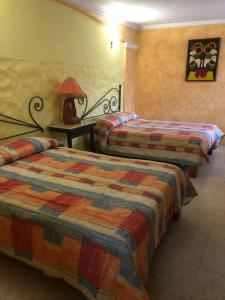 una camera d'albergo con due letti e una lampada su un tavolo di Hotel Mezvall a Morelia