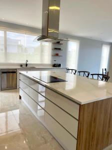 a kitchen with a large white counter with chairs at Altos de Tababela in Tababela