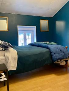 Un dormitorio con una cama con paredes azules y una ventana en QUERTINEUX Historic 4 Châteaux Lastours 3 Star 3 BED air conditioned apartment, en Lastours