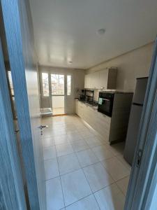 uma grande cozinha com piso em azulejo branco e electrodomésticos em Appart de luxe 27 ILOT9 em Oujda