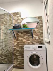 a washing machine in a bathroom with a shelf at Casa Daria in Râmnicu Vâlcea