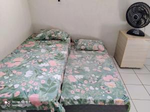 1 dormitorio con 1 cama con colcha de flores y ventilador en Marbelo Pernambuco Hostel, en Recife