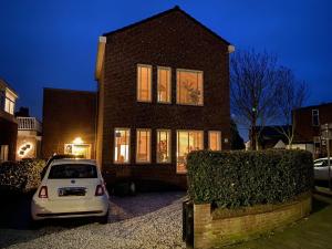 un coche blanco estacionado frente a una casa de ladrillo en Vakantiehuis De Zeeparel, en Zandvoort