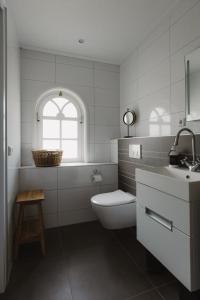 a white bathroom with a toilet and a sink at B&B Het Rijgebint in Molenaarsgraaf