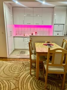 een keuken met een tafel en stoelen en roze verlichting bij Apartman Lana in Pale