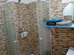 y baño con ducha y pared de ladrillo. en Casa Daria, en Râmnicu Vâlcea