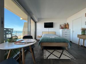 a bedroom with a bed and a table and a view at Superbe vue à 180° sur l'océan in Lacanau