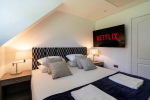 a bedroom with a bed with a netflix sign on the wall at Tranquil Country Retreat With Access to Gym, Golf & Spa in Deanshanger