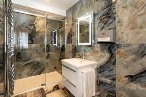 a bathroom with a sink and a shower and a mirror at Tranquil Country Retreat With Access to Gym, Golf & Spa in Deanshanger