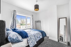 a bedroom with a bed with blue pillows and a window at 3-Bed, Sleeps 6, Near M1/M62 in Morley