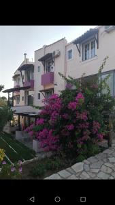 un gran edificio con flores rosas delante en Koralli Sea View Hotel, en Káto Achaḯa
