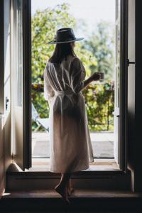 a woman in a white dress and hat looking out a window at IN2 BnB in Solothurn