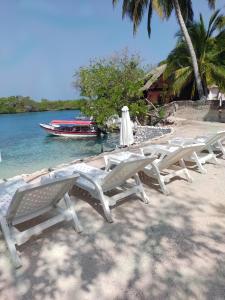 a group of lounge chairs on a beach with a boat at PARAISO REAL in Isla Grande