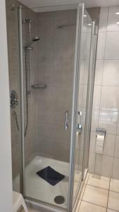 La salle de bains est pourvue d'une douche avec une porte en verre. dans l'établissement Villa Seegatt Wohnung 008, à Norderney
