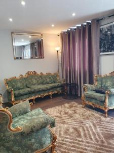 a living room with green couches and a mirror at Crestfield Lodge in Thamesmead