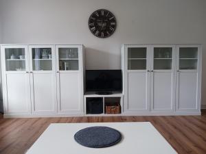 a living room with white cabinets and a clock on the wall at HARZ-LIEBE Lautenthal in Langelsheim