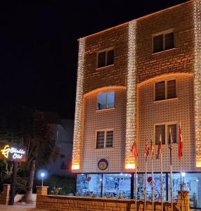 un edificio de ladrillo con banderas delante de él por la noche en ANTALYA Konyaaltı Gündüz Otel, en Antalya