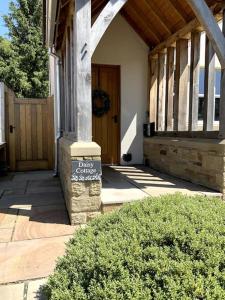 Daisy Cottage, delightful 3 bedroom cottage in village location في Barrowford: الشرفة الأمامية للمنزل مع وجود علامة عليه