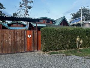 ein Haus mit einem Holztor und einer Hecke in der Unterkunft Pura Vida Cabinita in Uvita