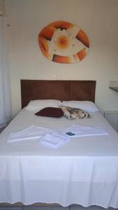 uma cama com lençóis brancos e uma cabeceira castanha em POUSADA MEGA em Marataízes