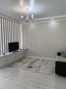 ein Wohnzimmer mit einem TV und einem Sofa in der Unterkunft VIP квартира in Oral