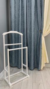 einem weißen Stuhl vor einem blauen Duschvorhang in der Unterkunft VIP квартира in Oral