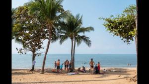 um grupo de pessoas em pé em uma praia com palmeiras em Heartbeat Crypto Jomtien 05 em Praia de Jomtien