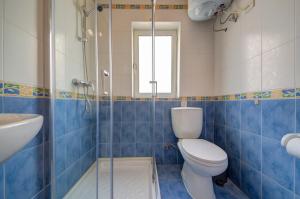La salle de bains est pourvue de carrelage bleu, de toilettes et d'un lavabo. dans l'établissement Violet Court Apartments and Penthouse in St Julian's By ShortletsMalta, à San Ġiljan