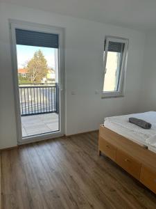 a bedroom with a bed and a sliding glass door at Neubauwohnung gleich bei der Bushaltestelle - Apartment 2a in Vienna