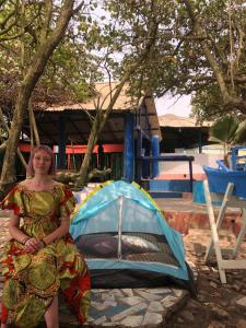 a woman in a dress standing next to a tent at Rising Phoenix in Accra
