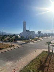 una strada vuota con un edificio bianco e palme di Al Hoceima Mini Villa ad Al-Ḥoseyma