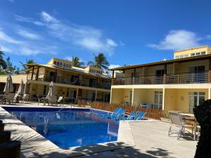 a resort with a swimming pool in front of a building at Vilage beira-mar Itacimirim in Camaçari