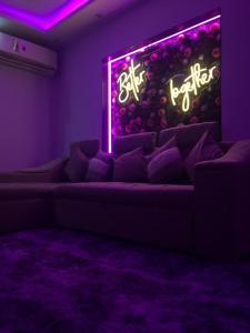 a living room with a couch with a neon sign at Discover Inn in Alexandria