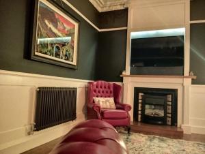 a living room with a red chair and a fireplace at Lorne View in Oban