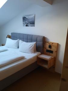 a bed with white pillows and a night stand next to it at Stockingbauer in Leogang