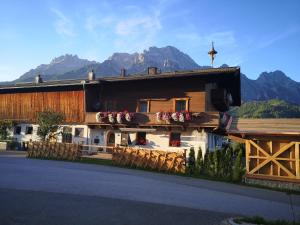 una casa con dei fiori sul lato con le montagne di Stockingbauer a Leogang