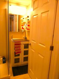 La salle de bains est pourvue d'un lavabo et d'une porte blanche. dans l'établissement Lovely comfy home private bath in central Calgary, à Calgary