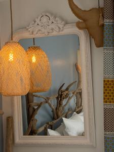 a mirror with a lamp and a tree reflection in it at Hôtel Le Neptune en Camargue in Saintes-Maries-de-la-Mer