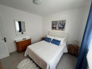 a bedroom with a white bed with blue pillows at Casa Mar Azul. in Tinajo +19 photos