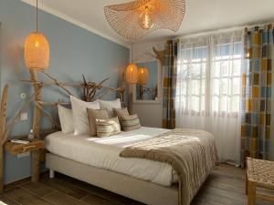 una camera da letto con letto, lenzuola e cuscini bianchi di Hôtel Le Neptune en Camargue a Saintes-Maries-de-la-Mer