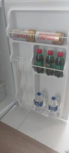 an open refrigerator with bottles of water and a bagel at Aconchego e conforto - Studio próximo a UFMG, Mineirão, Pampulha, Centro in Belo Horizonte