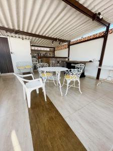 Una habitación con mesas y sillas blancas en un edificio. en Casa com Churrasqueira próx a Praia das Astúrias, en Guarujá 7 fotos más